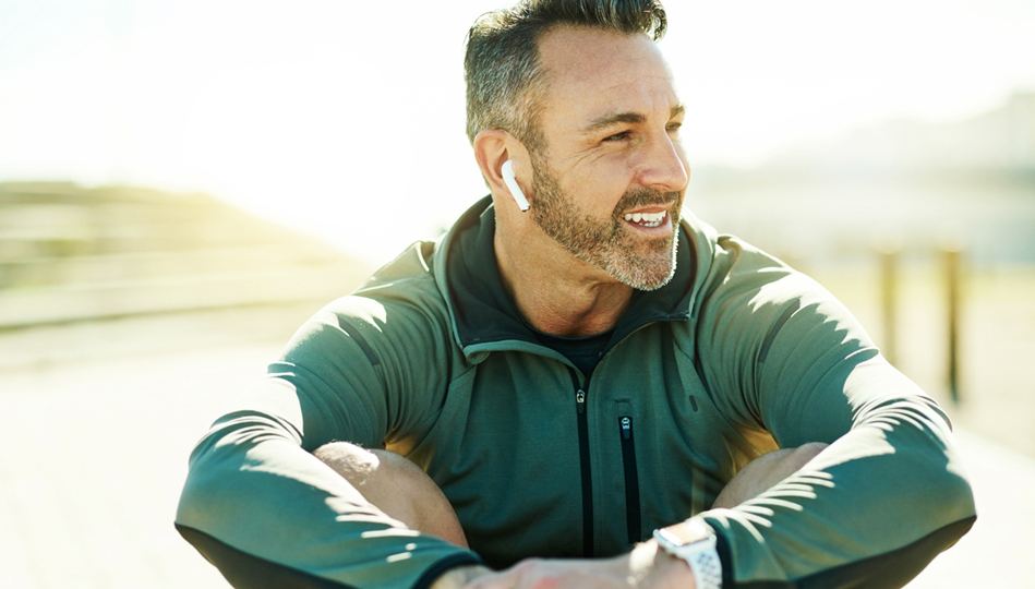 A man smiles while listening to music after a run.