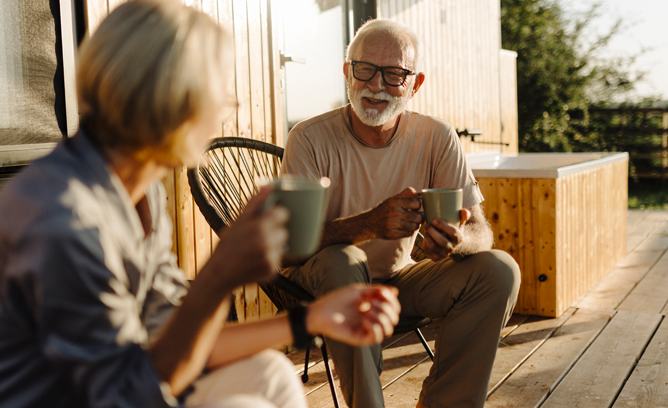 Two people making conversation on the porch over coffee.