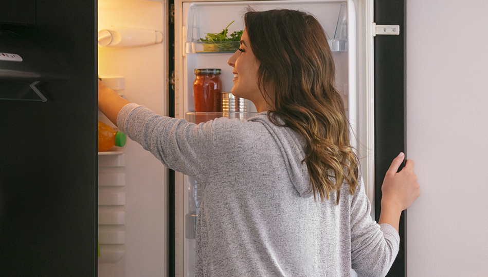 A woman reaches in the refrigerator for a healthy snack.