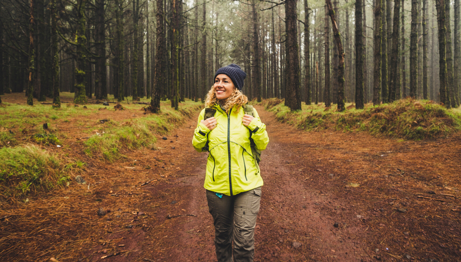 A woman is being present in nature on her walk.