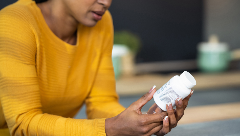 A person studies the label on their medication bottle.