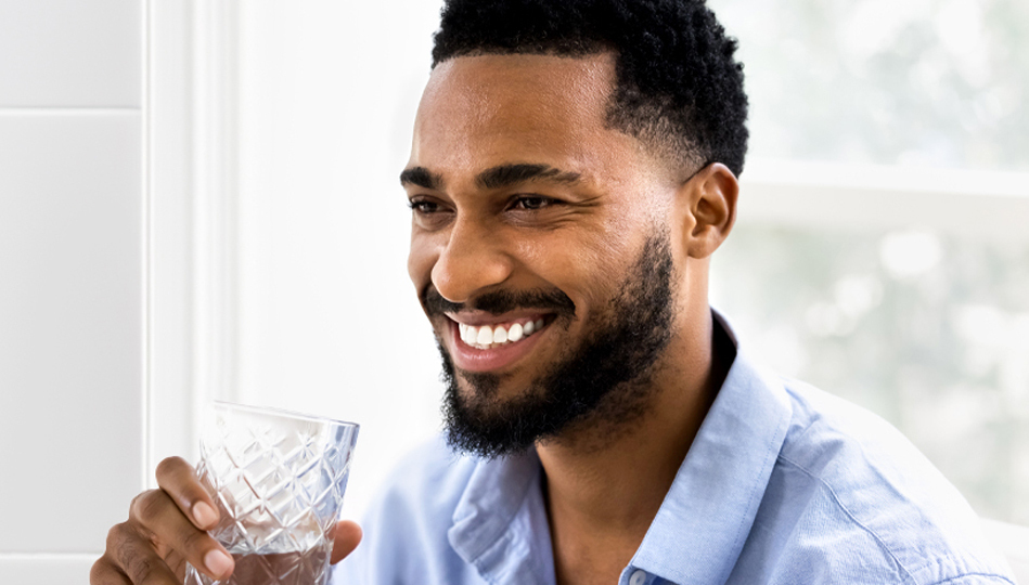 A man finishes his glass of water after taking his medication.