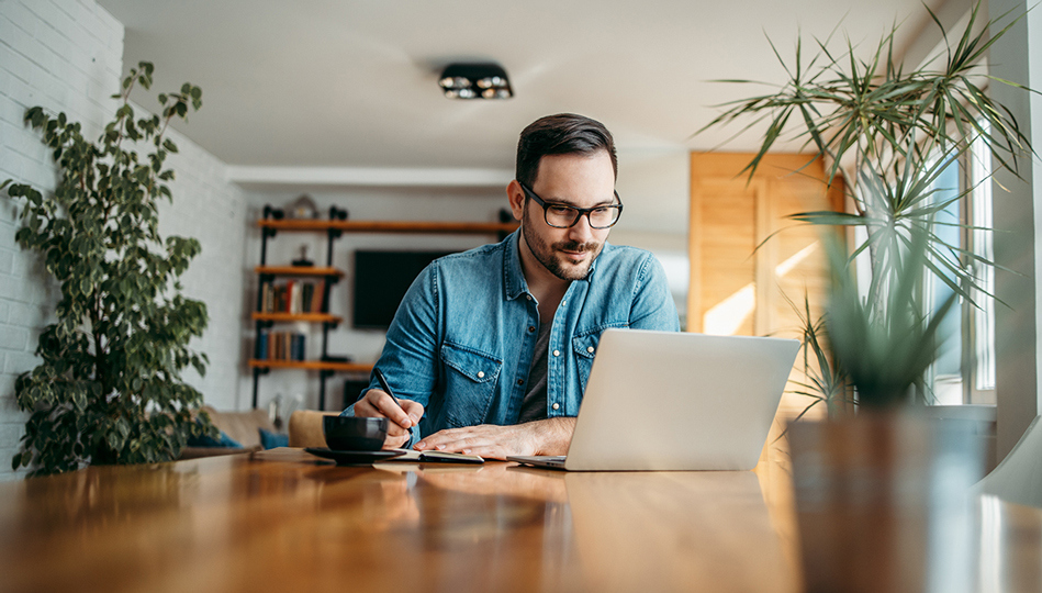 A man sits down at his computer to track his goals.