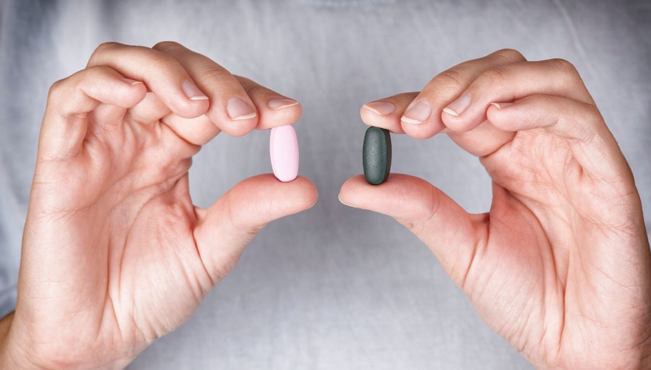 Two hands holding pills