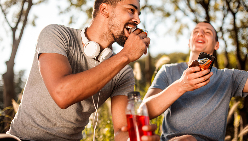 A pair of friends recover with protein bars after a run together.