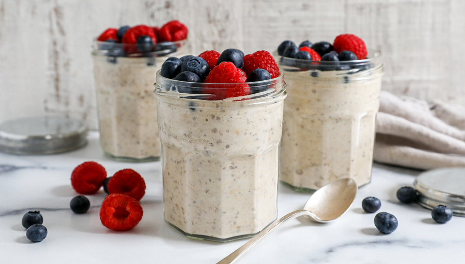 Three mason jars of overnight oats topped with raspberries and blueberries