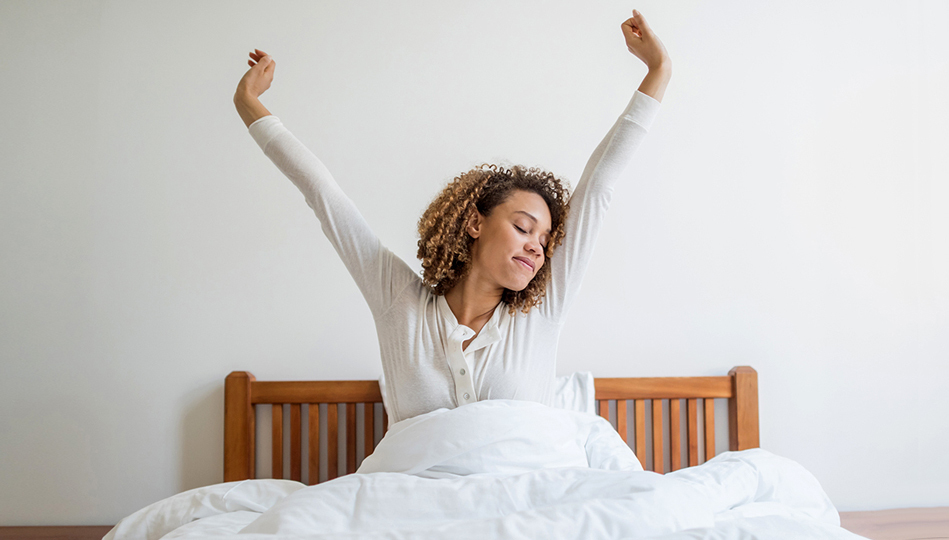 A woman stretching as she awakes from incredibly restful sleep.