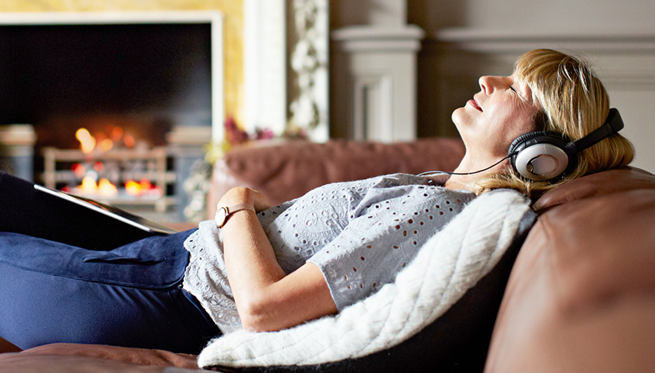 A woman lays back while listening to music through her headphones.