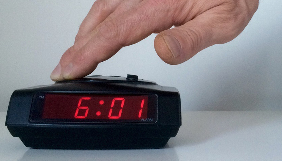 A person shuts off their morning alarm.