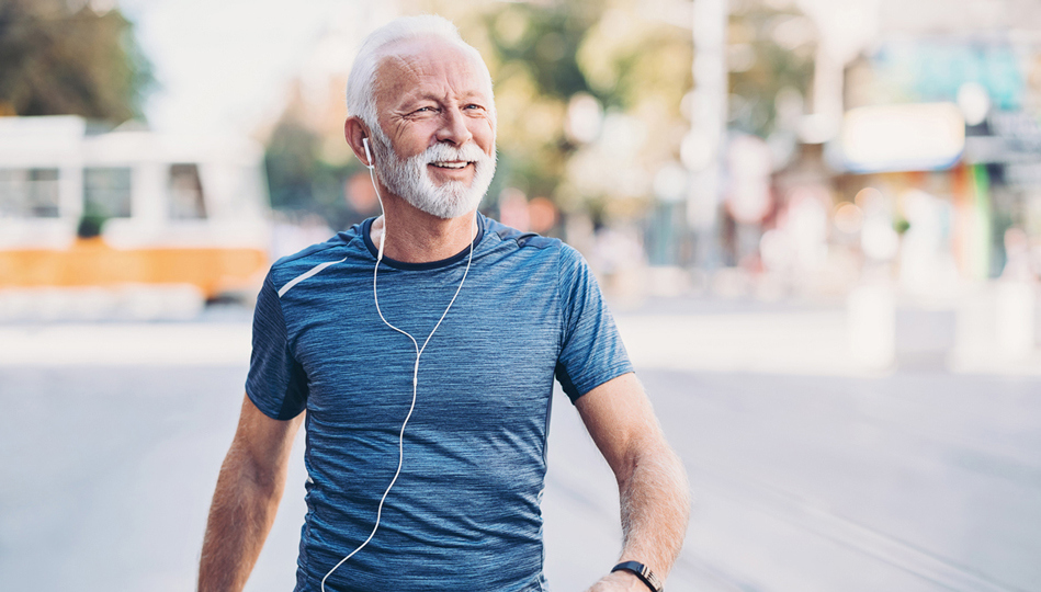 A man enjoys a walk outside while listening to music through his headphones.